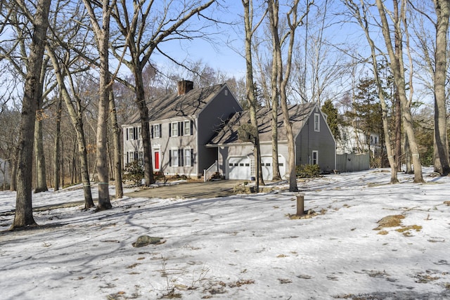 colonial inspired home with a garage and a chimney