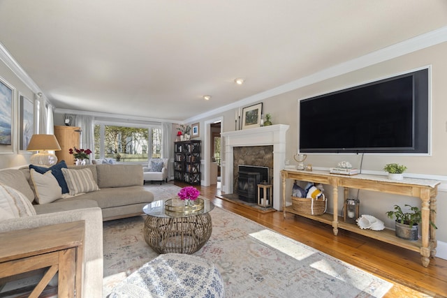 living area featuring ornamental molding, a fireplace with raised hearth, and wood finished floors