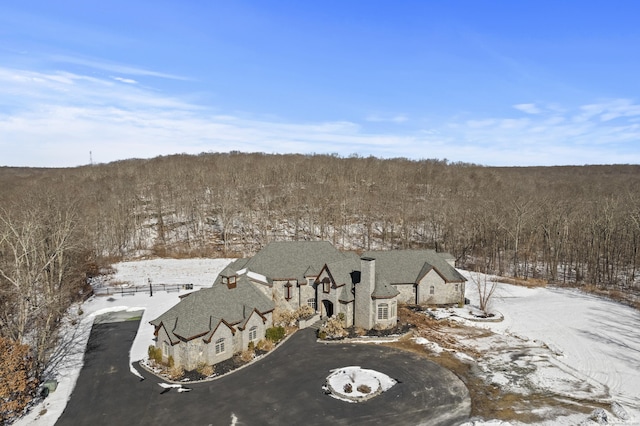 snowy aerial view featuring a wooded view