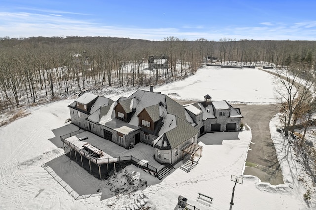 snowy aerial view featuring a forest view