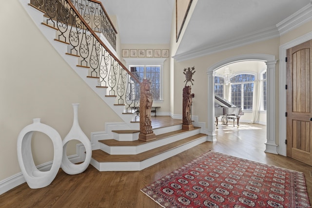 entryway featuring ornate columns, plenty of natural light, crown molding, and wood finished floors