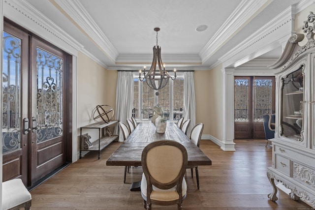 dining space featuring wood finished floors, french doors, and a raised ceiling