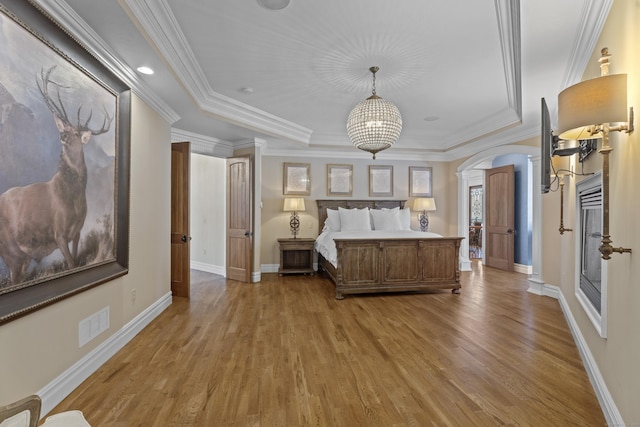 unfurnished bedroom with light wood-type flooring, a tray ceiling, and crown molding