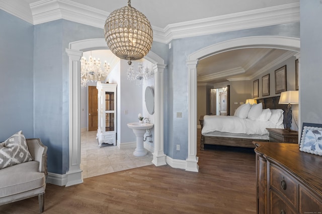 bedroom featuring arched walkways, wood finished floors, a chandelier, and ornate columns