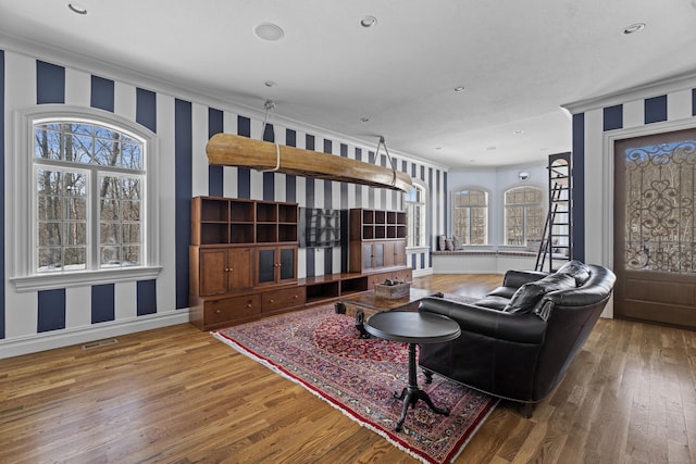 living room with wallpapered walls, visible vents, baseboards, and wood finished floors