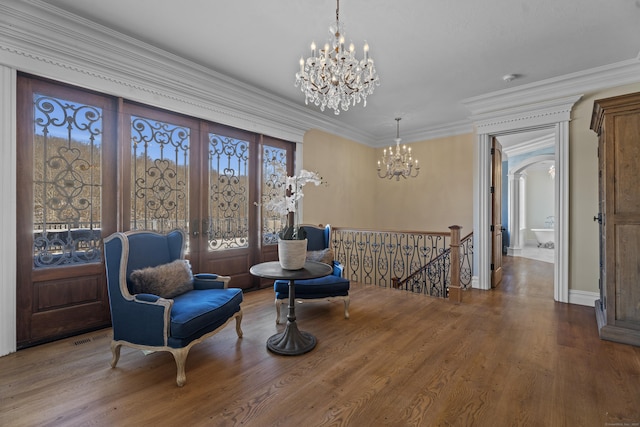 sitting room with arched walkways, a notable chandelier, ornamental molding, an upstairs landing, and wood finished floors