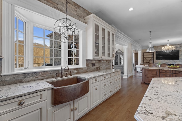 131 Burr Hill Rd, Killingworth, CT 06419 - kitchen with decorative backsplash, light stone countertops, glass insert cabinets, a chandelier, and a sink