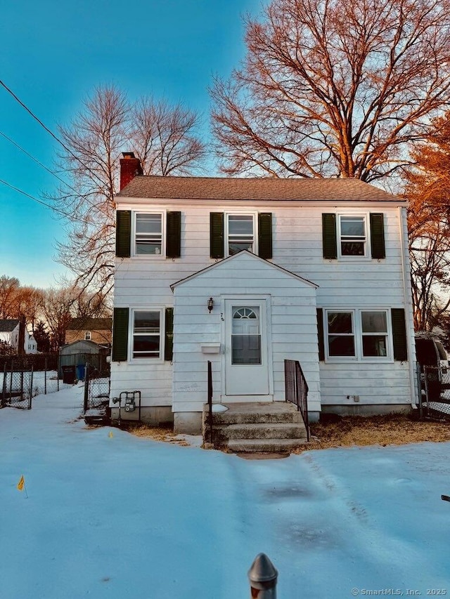 view of front of house featuring entry steps, a chimney, and fence