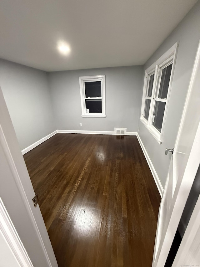 unfurnished room with visible vents, baseboards, and wood finished floors