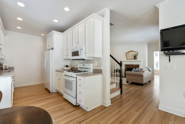 kitchen featuring decorative backsplash, white appliances, white cabinets, and light hardwood / wood-style floors