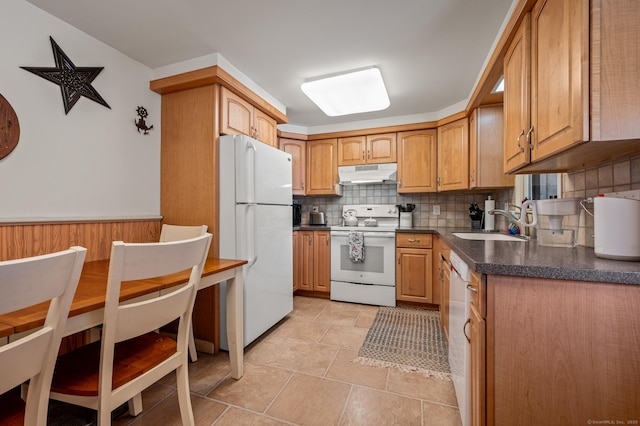 kitchen featuring tasteful backsplash, dark countertops, a sink, white appliances, and under cabinet range hood