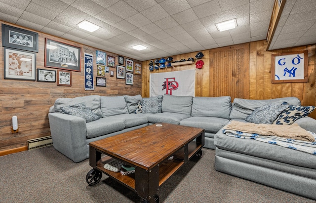 living area featuring wood walls, baseboard heating, and dark colored carpet