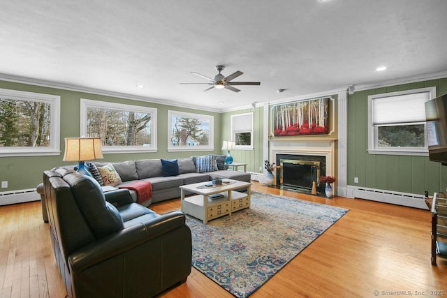 living area featuring light wood-style floors, a fireplace with flush hearth, a baseboard heating unit, and crown molding