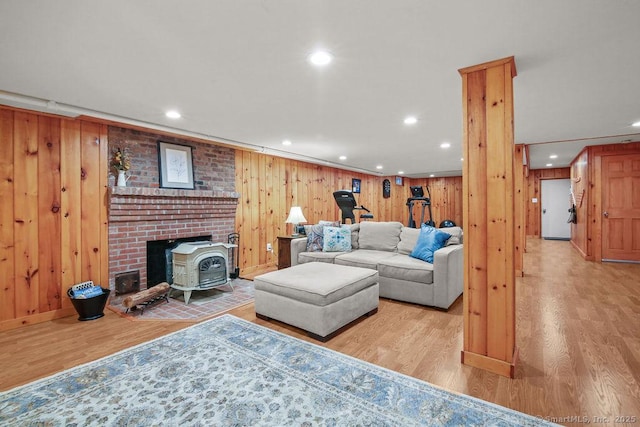 living room with recessed lighting, a wood stove, wooden walls, and light wood finished floors