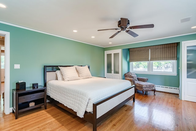 bedroom with a baseboard radiator, multiple windows, and light wood finished floors