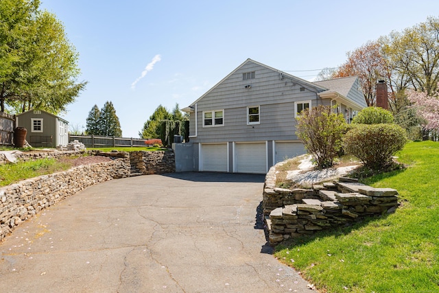 view of home's exterior featuring driveway, a garage, and fence