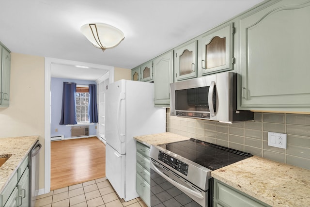 kitchen featuring appliances with stainless steel finishes, tasteful backsplash, baseboard heating, green cabinets, and light tile patterned floors