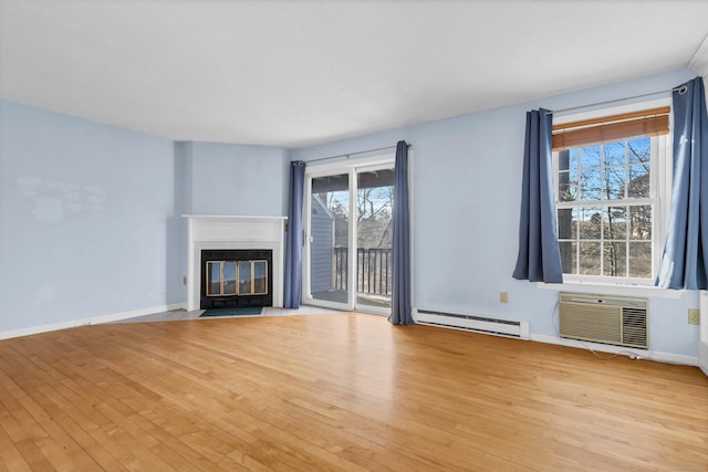 unfurnished living room with light wood-type flooring, a wall unit AC, and a baseboard radiator