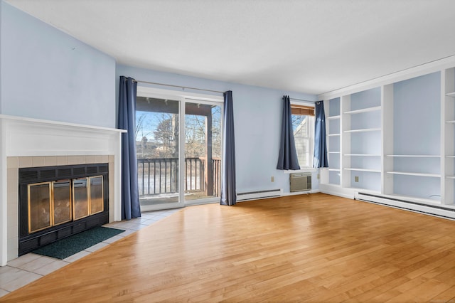 unfurnished living room featuring light hardwood / wood-style flooring, an AC wall unit, a baseboard heating unit, and a tiled fireplace