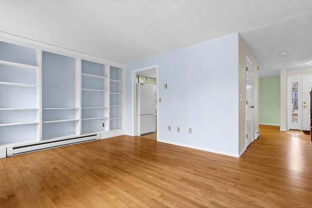 spare room featuring light hardwood / wood-style flooring, built in shelves, and baseboard heating