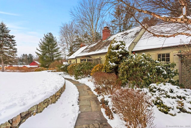 view of snow covered exterior featuring a chimney