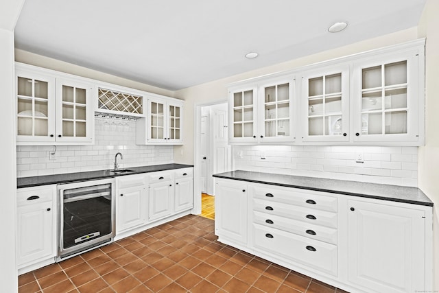 kitchen featuring glass insert cabinets, dark countertops, and beverage cooler