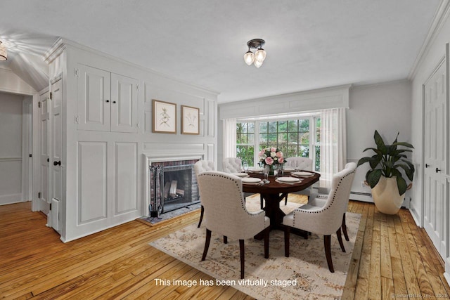 dining room featuring light wood-type flooring, a fireplace, and ornamental molding