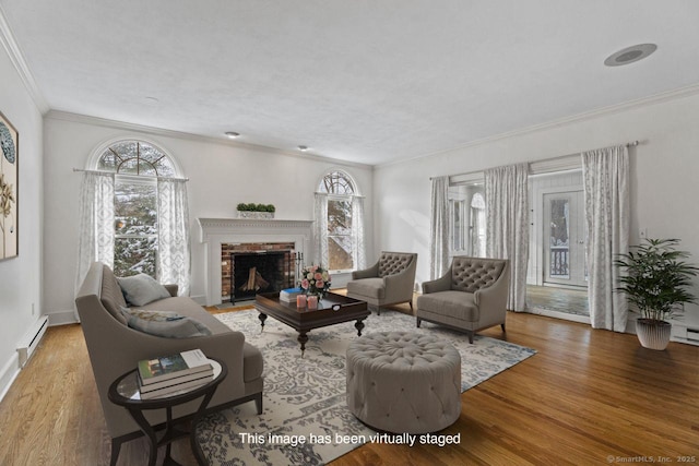 living area featuring a wealth of natural light, a baseboard heating unit, and wood finished floors