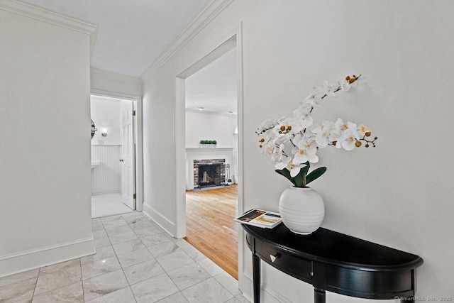 hallway with marble finish floor, baseboards, and ornamental molding