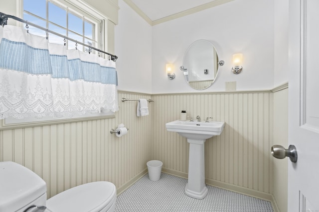 full bath featuring curtained shower, wainscoting, toilet, and crown molding