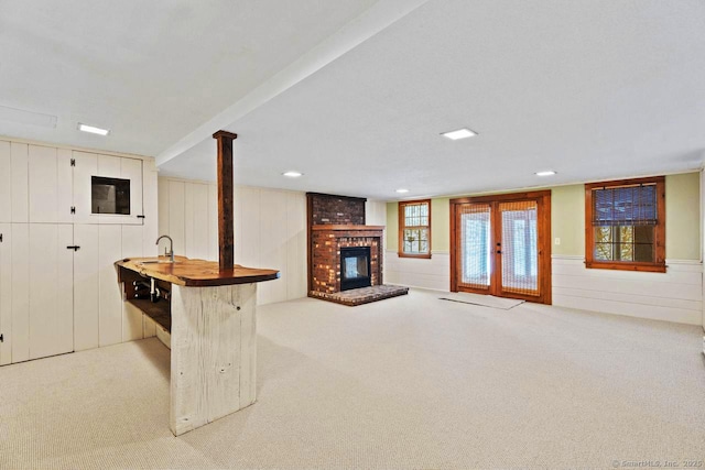 unfurnished living room with light carpet, a fireplace, and a sink