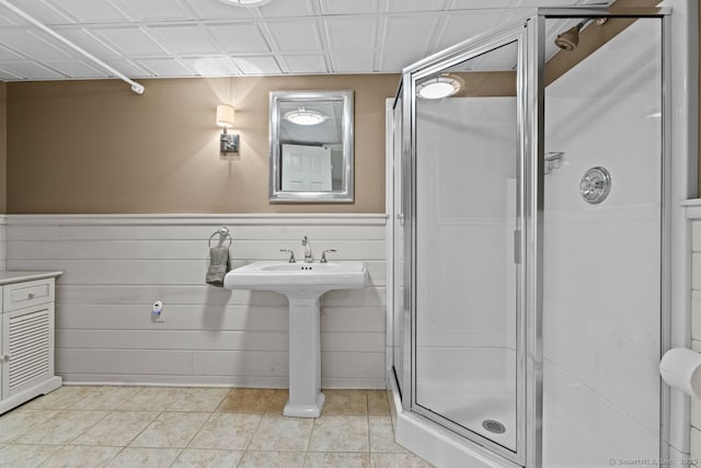 bathroom featuring an ornate ceiling, a shower stall, tile patterned flooring, and wainscoting