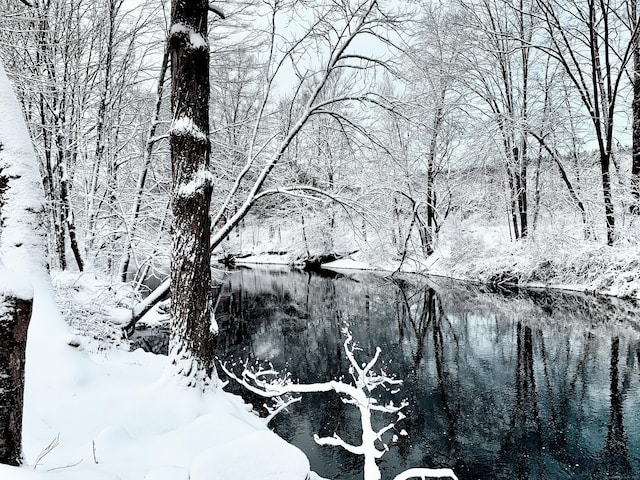 view of snow covered land with a water view