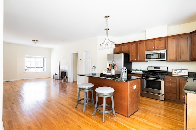 kitchen featuring a center island, a breakfast bar, decorative light fixtures, appliances with stainless steel finishes, and light wood-style floors