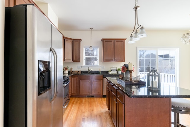 kitchen featuring appliances with stainless steel finishes, a sink, light wood-style floors, and pendant lighting