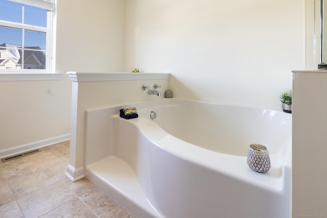 bathroom with a garden tub, baseboards, and visible vents