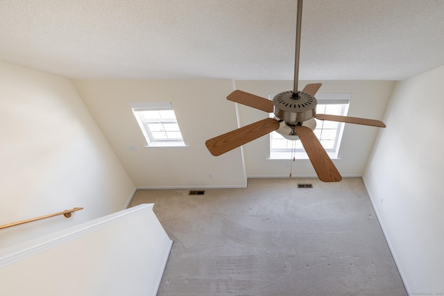 bonus room with light colored carpet, a skylight, visible vents, and a textured ceiling