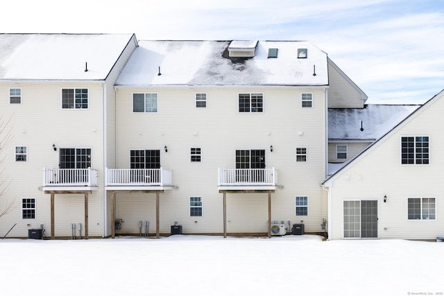 snow covered back of property with central AC and a balcony