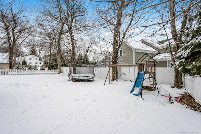 yard covered in snow featuring a playground and a trampoline