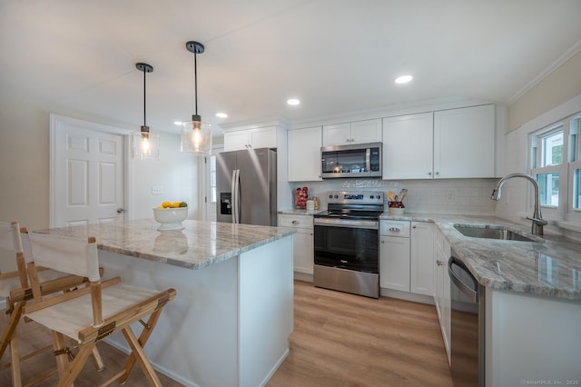 kitchen with a breakfast bar area, a sink, stainless steel appliances, white cabinetry, and tasteful backsplash