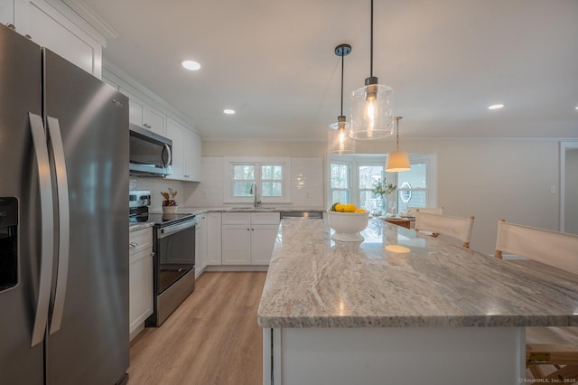 kitchen with light wood-style flooring, a sink, a kitchen island, white cabinetry, and appliances with stainless steel finishes