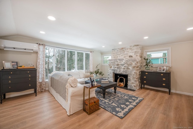 living room with a wealth of natural light, wood finished floors, a fireplace, and a wall unit AC