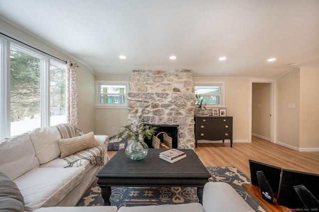 living room with wood finished floors, baseboards, a fireplace, recessed lighting, and crown molding