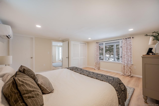 bedroom featuring light wood finished floors, baseboards, a wall mounted air conditioner, recessed lighting, and a closet