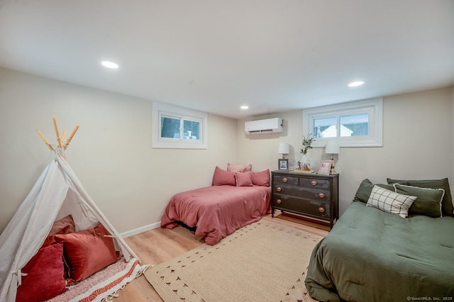 bedroom featuring a wall mounted air conditioner, baseboards, wood finished floors, and recessed lighting