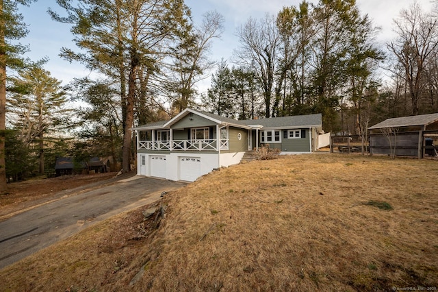 view of front of house with aphalt driveway, a garage, covered porch, and a front yard