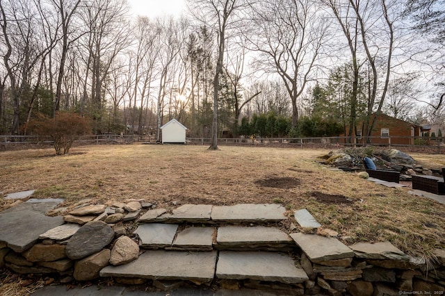 view of yard featuring an outbuilding, a shed, and fence