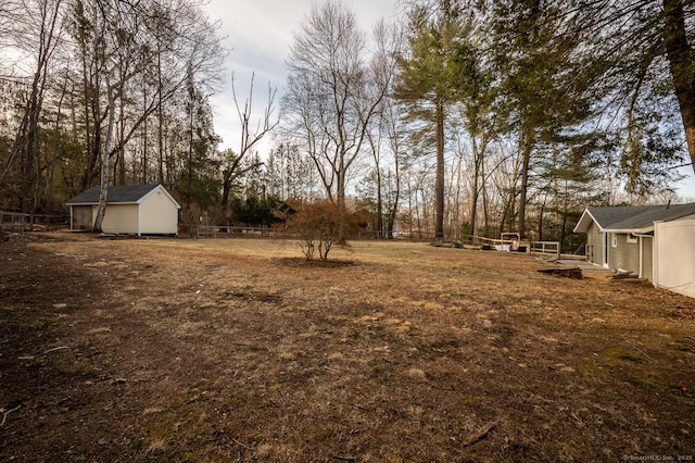 view of yard featuring a storage unit, an outdoor structure, and fence