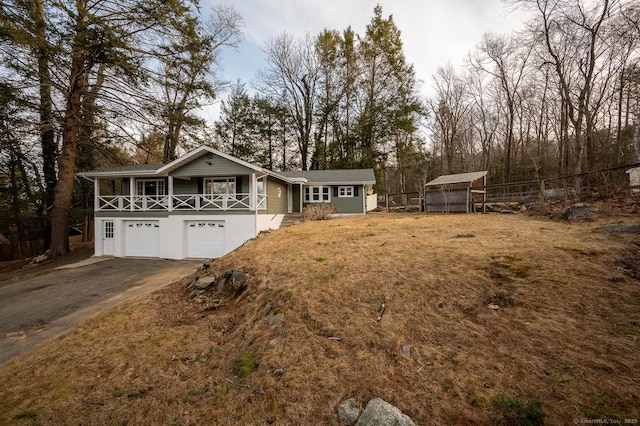 view of front facade with a porch, an attached garage, a front yard, and driveway