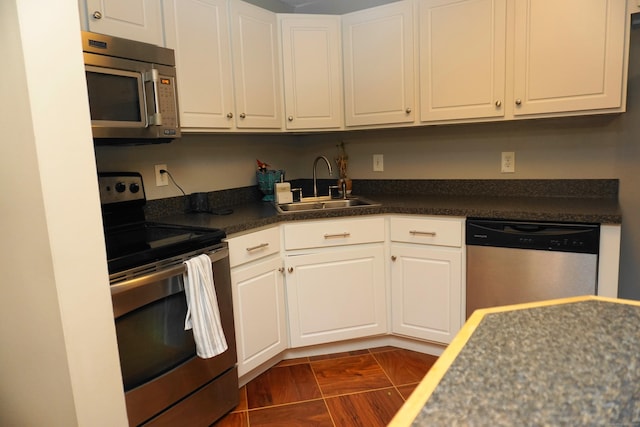 kitchen with sink, appliances with stainless steel finishes, white cabinets, and dark hardwood / wood-style floors